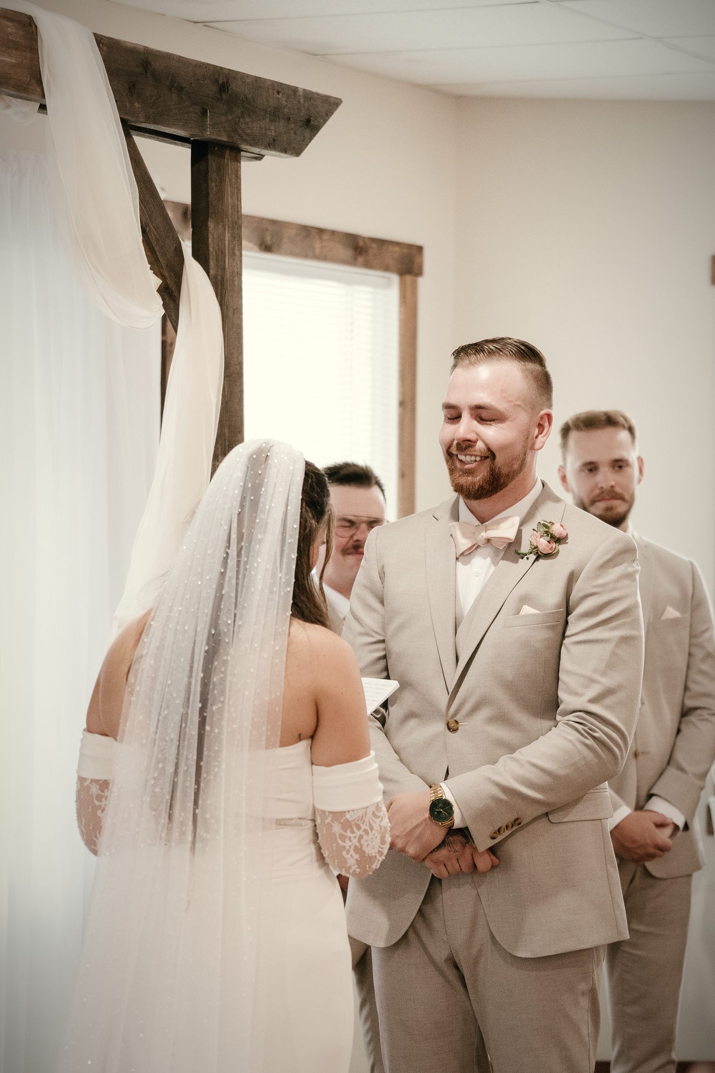 The groom laughing as his bride speaks her vows