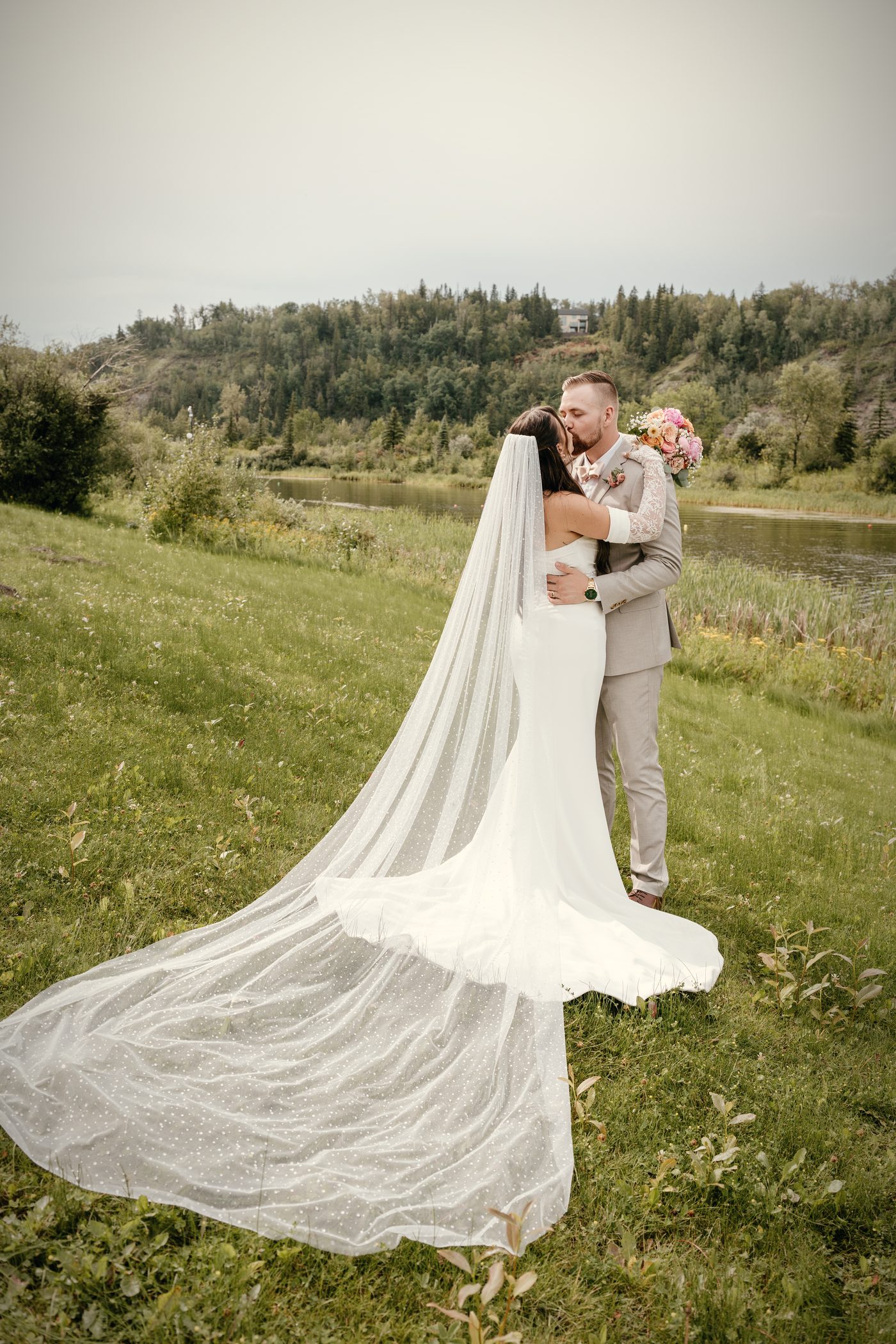 A couple embracing at the top of the slope, a cathedral veil spread behind them