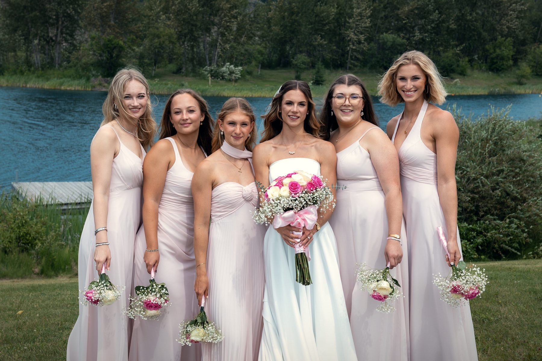 Bridesmaids in blush with their bouquets at the water's edge