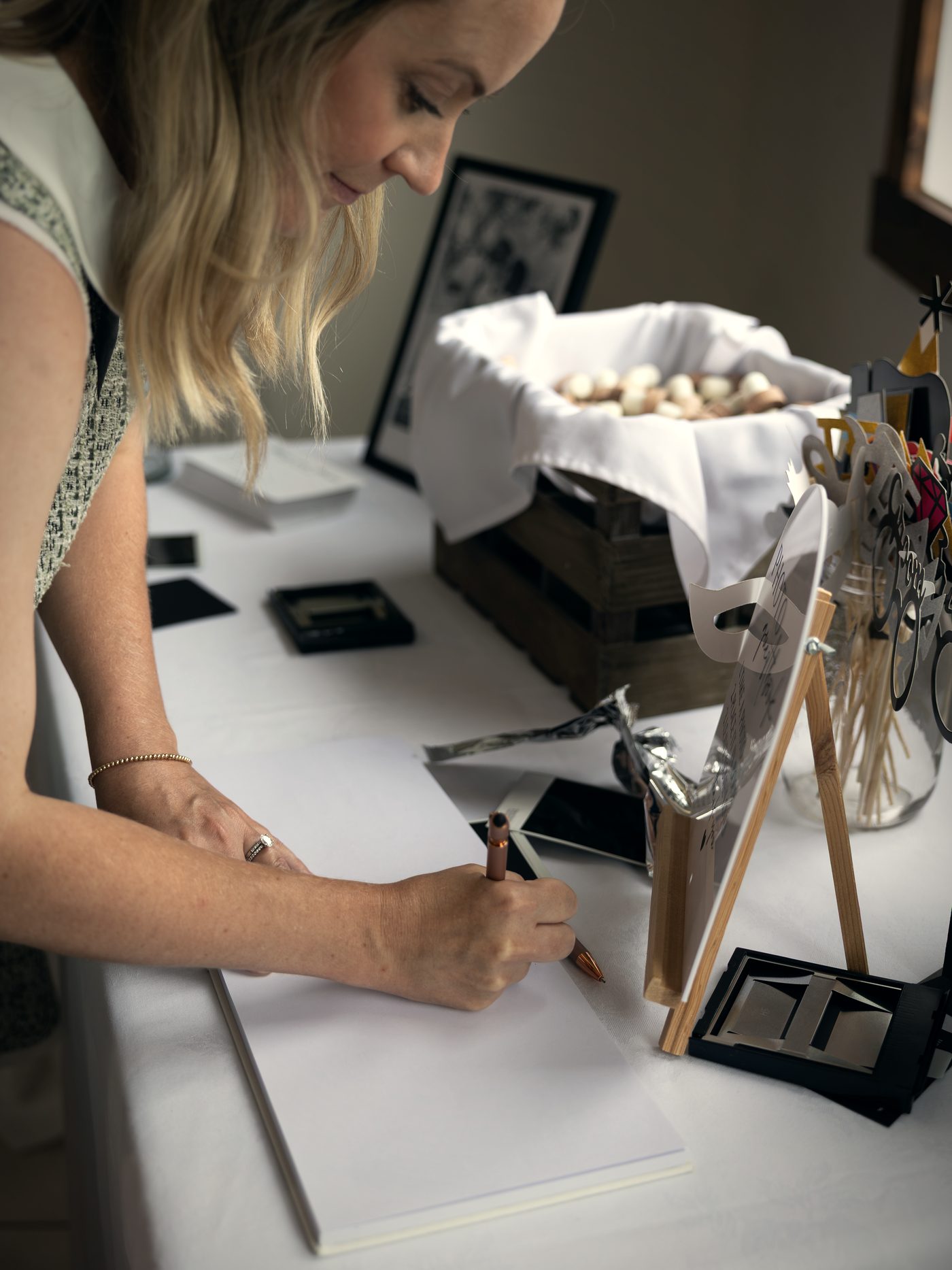 A guest signing the book by the window, a basket of favours beside her