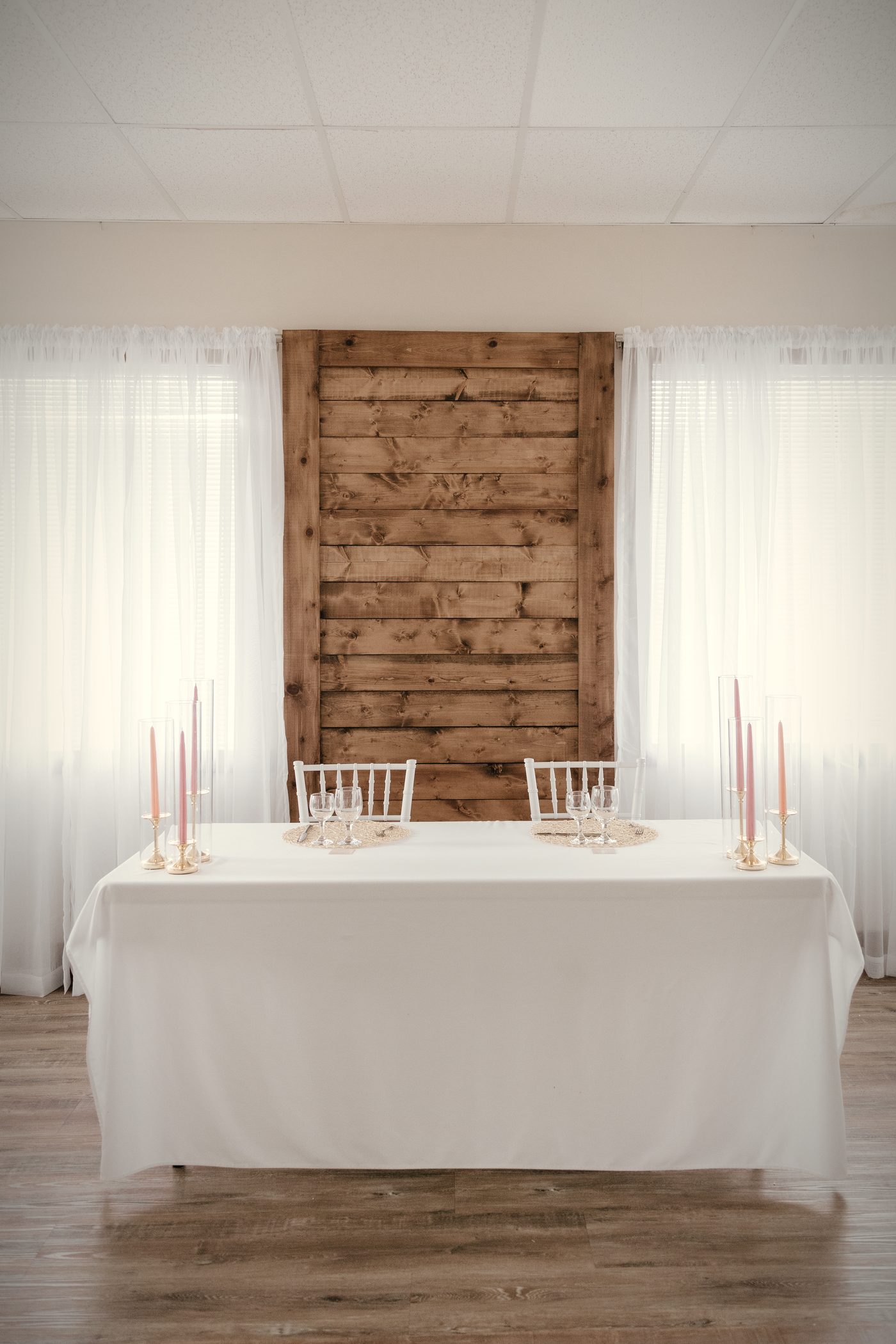 The head table set against the wood feature wall, white linen, tapers, parquet floor in front