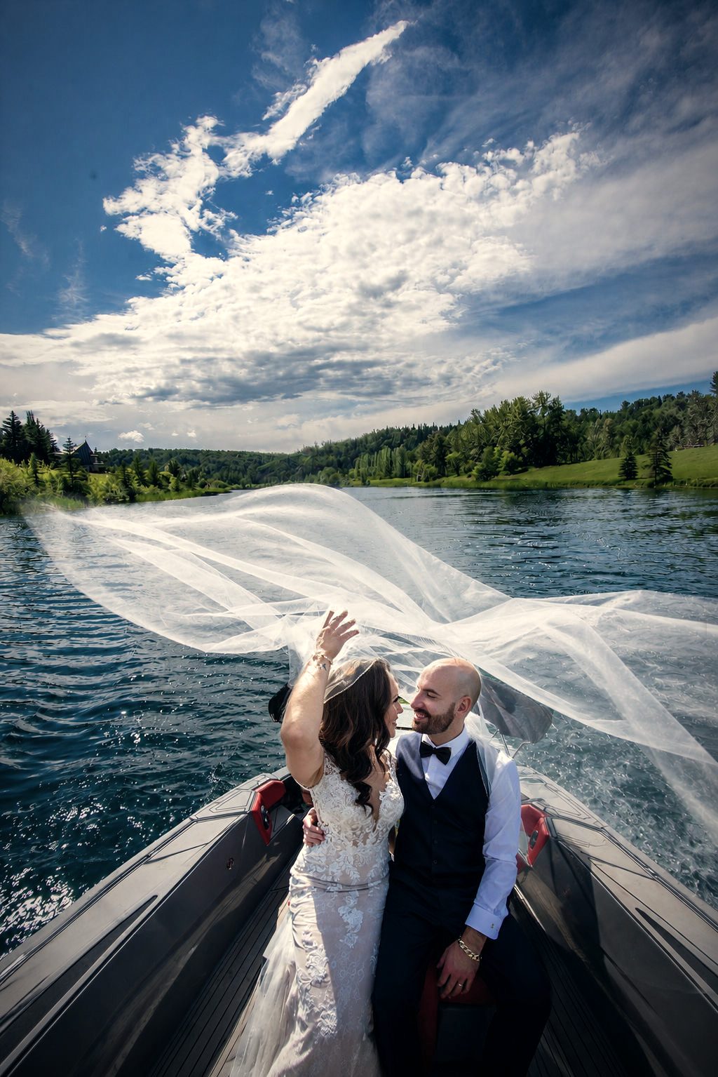 A bride's veil lifted over the bow of a boat, blue sky behind