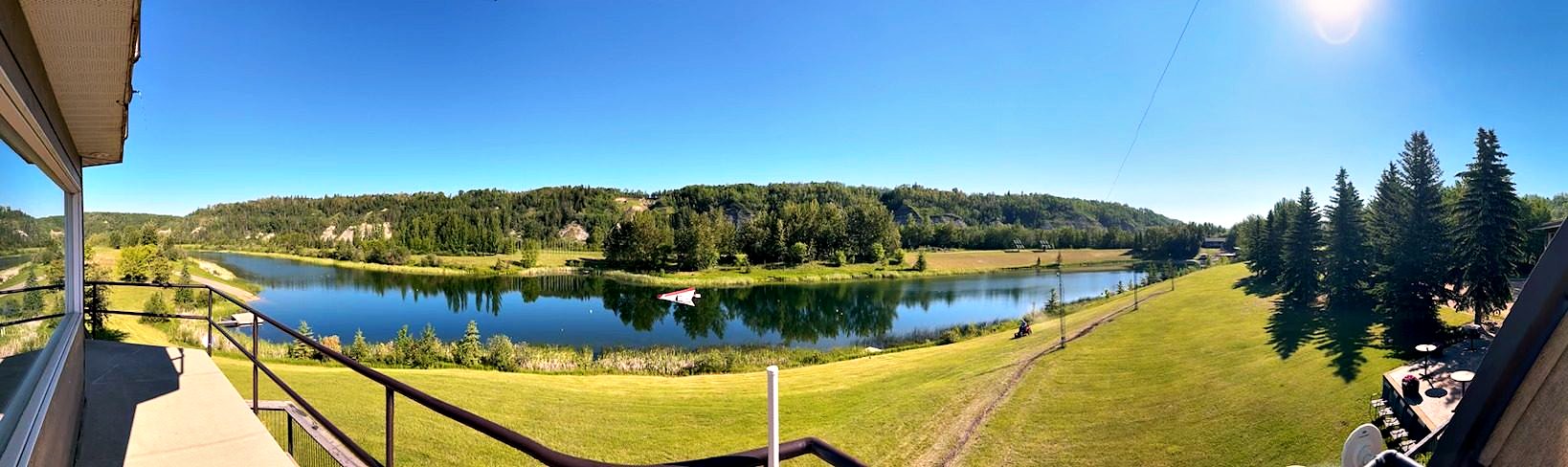 The view from the deck rail, mown lawn falling to the lake and the valley curving away west