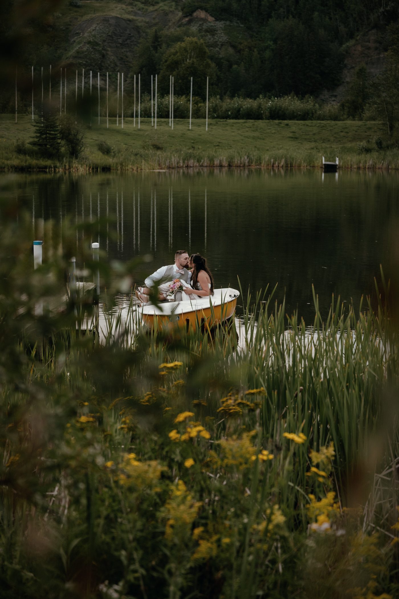 A rowboat on the lake seen through reeds and wildflowers