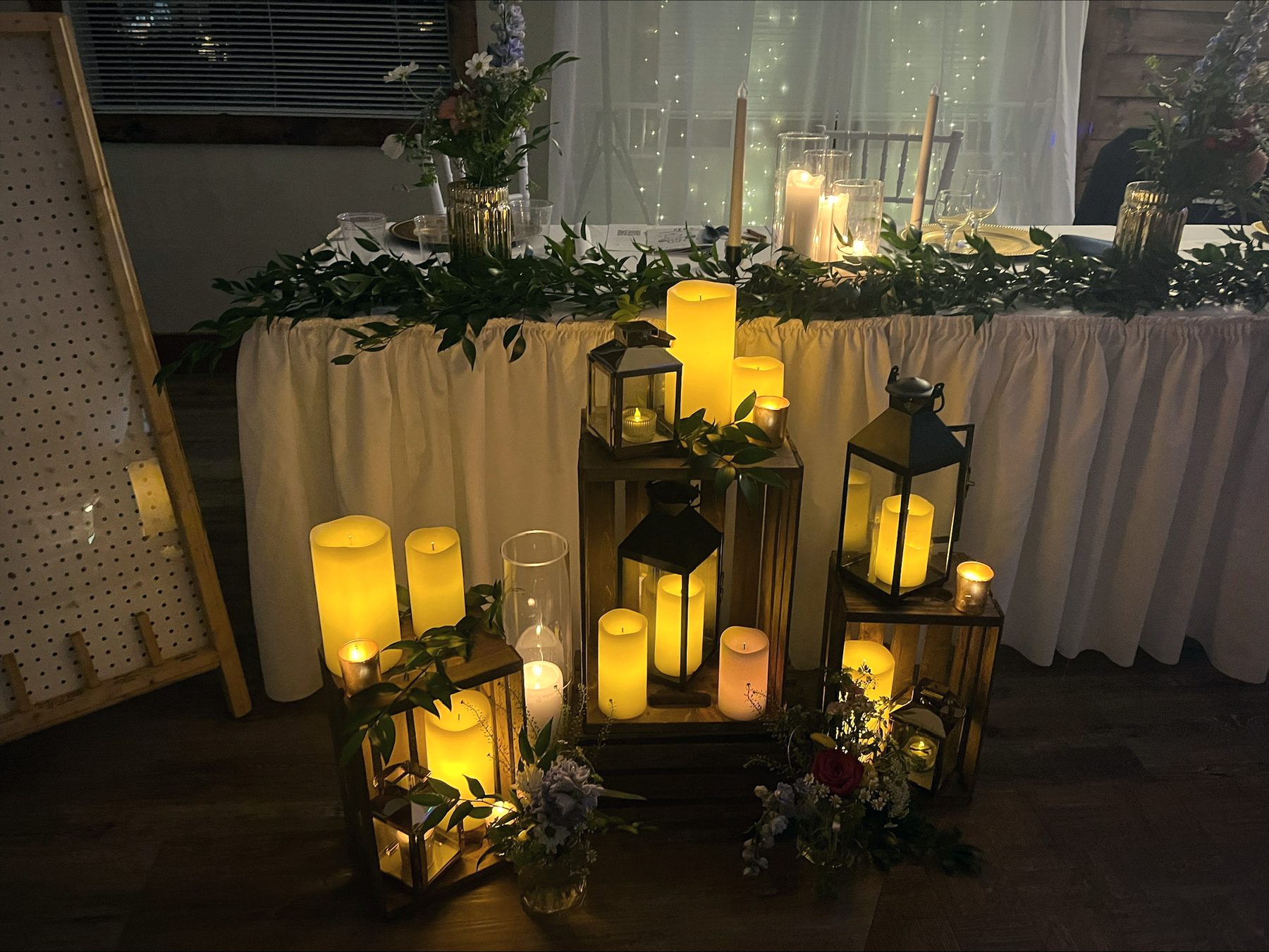 Candle lanterns and greenery along the head table at night