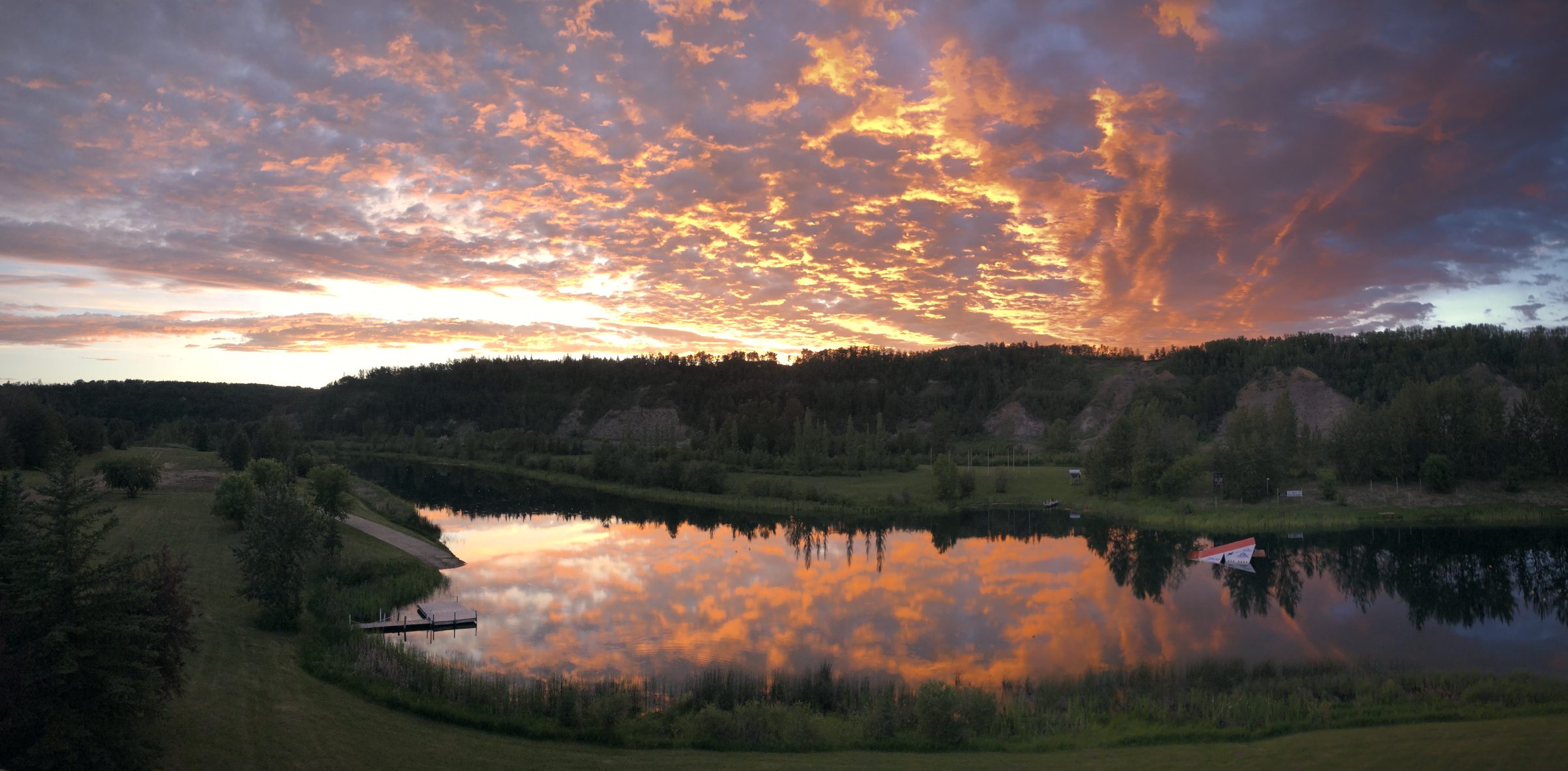 The sky ablaze at dusk, clouds the colour of embers doubled whole in the still lake
