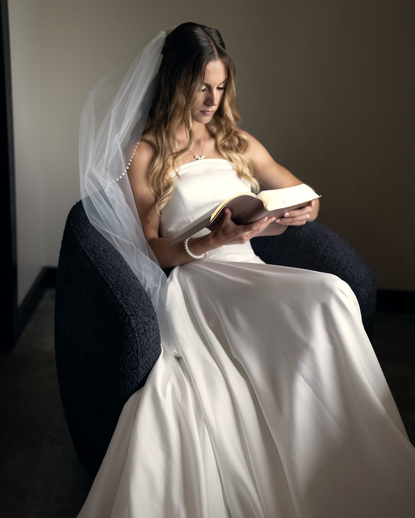 The bride reading a letter in the suite before the ceremony, her veil over her shoulder