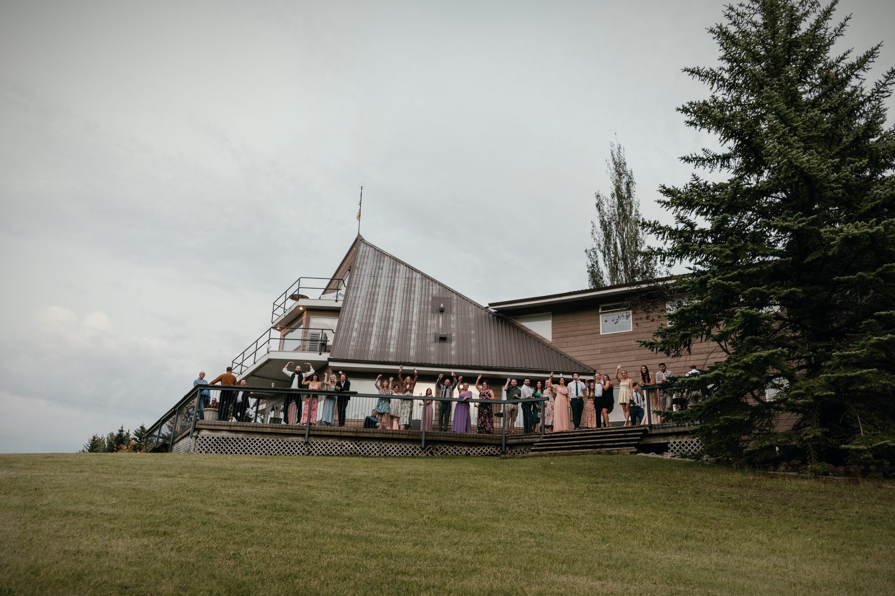 The wedding party gathered on the lodge deck, the lawn falling away in front of them